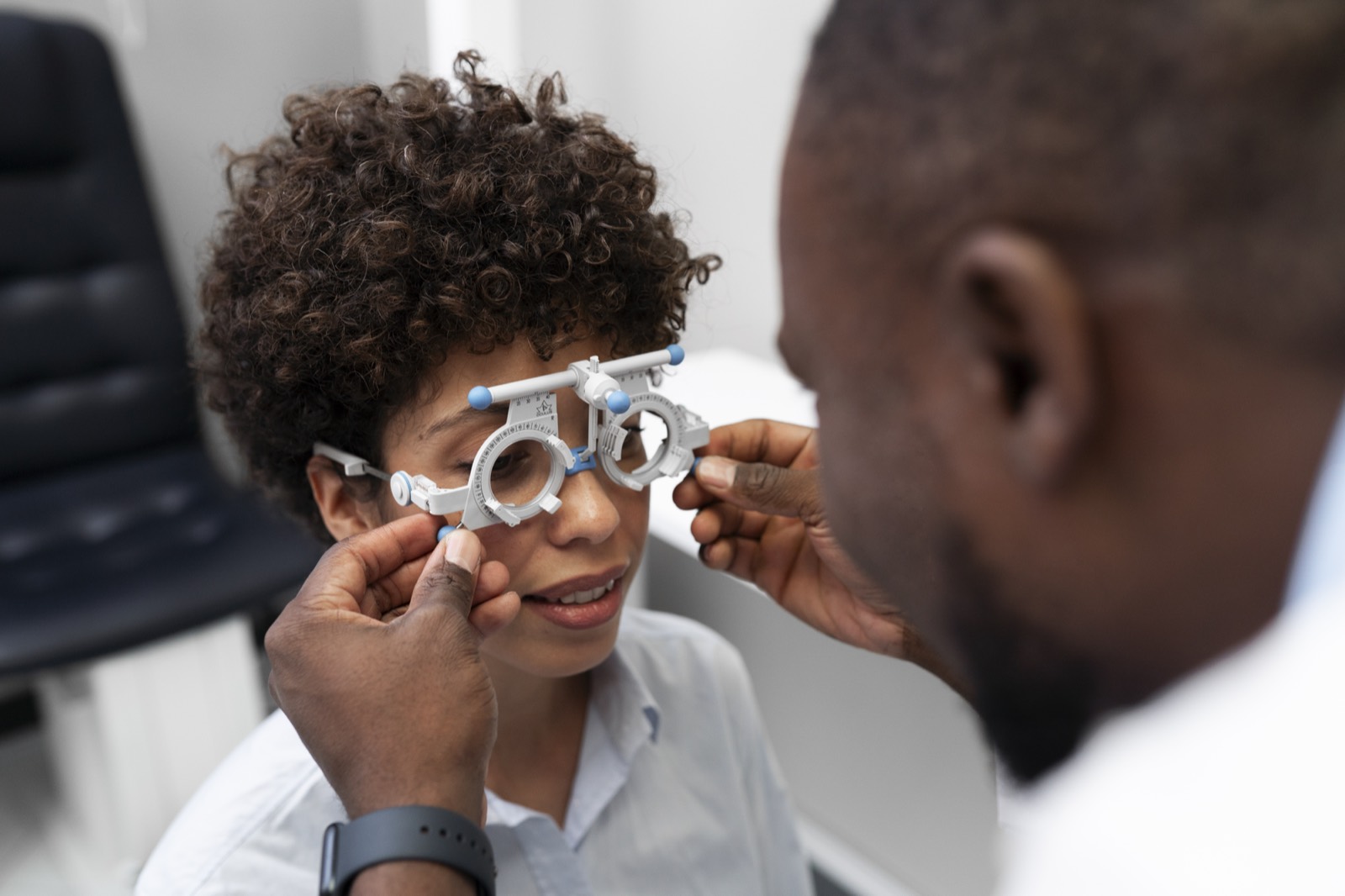 Optometrist fitting trial lenses for a young patient
