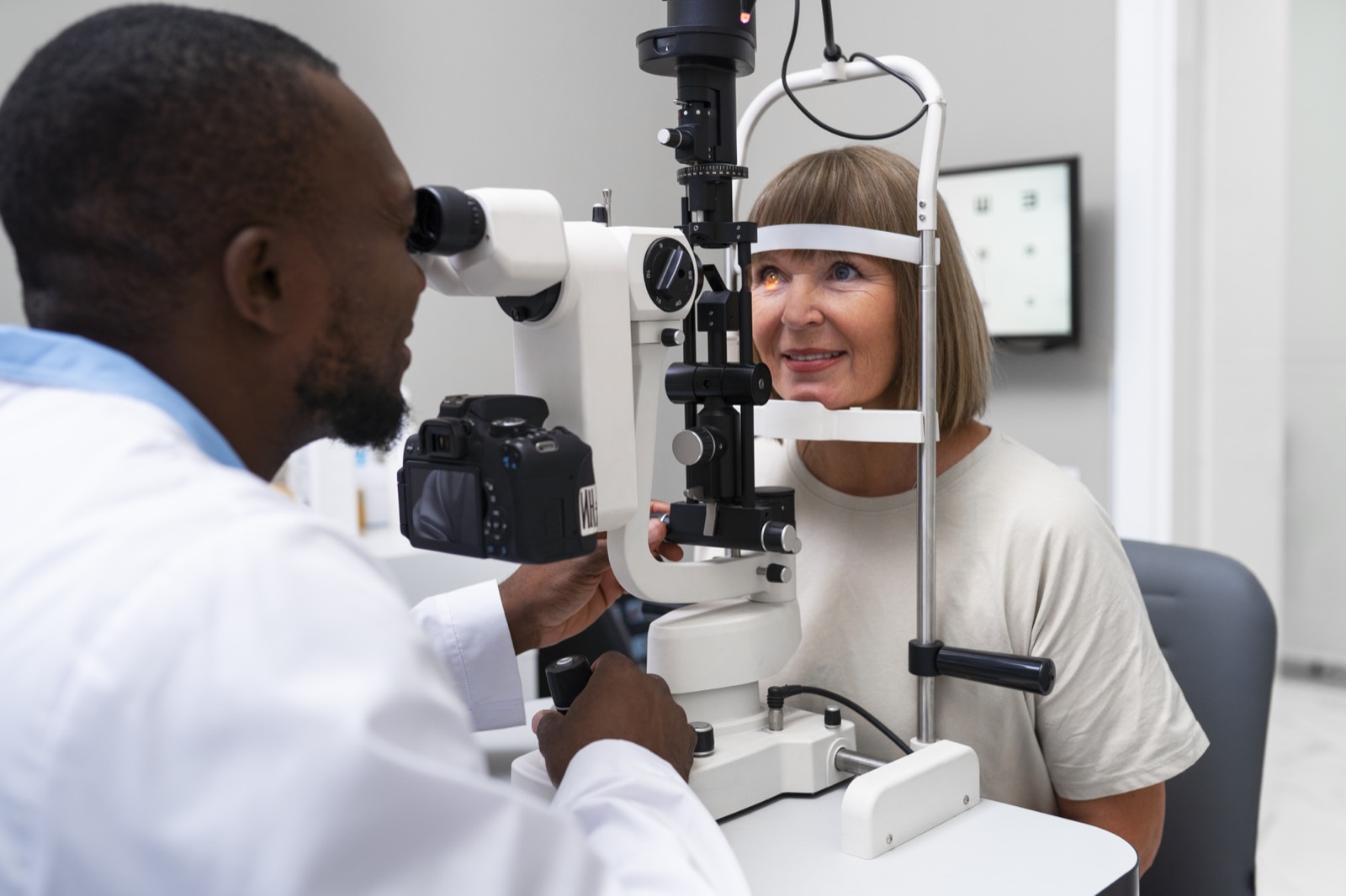 Optometrist examining a patient's eyes with a slit lamp
